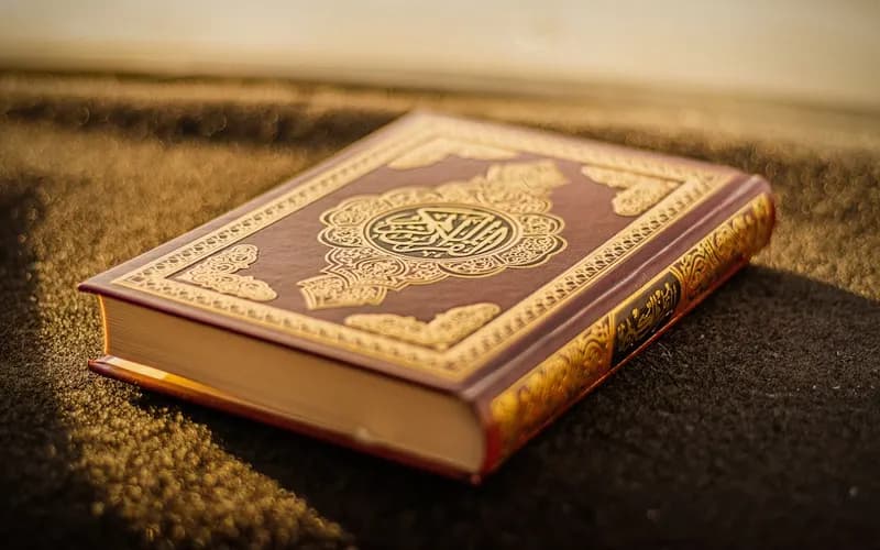 Beginner student practicing Arabic letters and Quran transliteration notes in a notebook