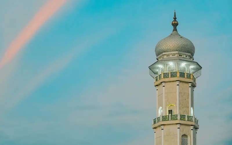People gathered at a mosque courtyard with a lantern glowing during the evening hours of Ramadan