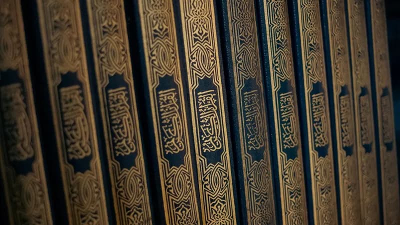 Muslim reading hadith book with prayer beads nearby representing study of the Prophet's Sunnah