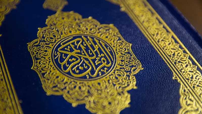 Quran and prayer mat arranged near a mosque window with soft daylight