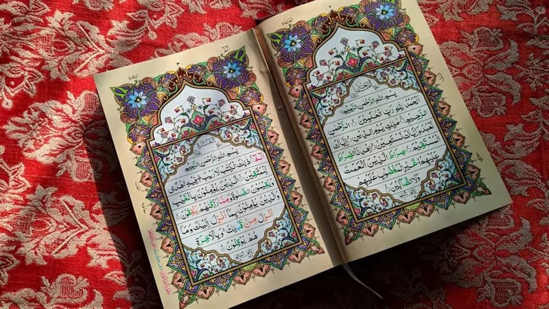 Sunlight streaming through window onto an open Quran resting on a wooden stand