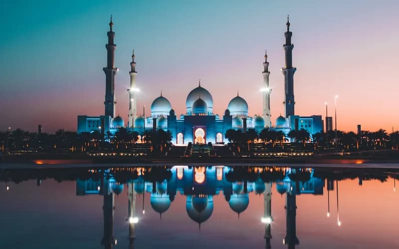 Muslims gathering outdoors for Eid prayer under a decorated mosque architecture